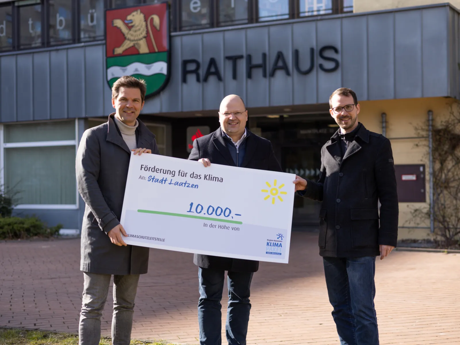 Drei Herren halten einen überdimensionierten Scheck für ein gemeinsames Bild.